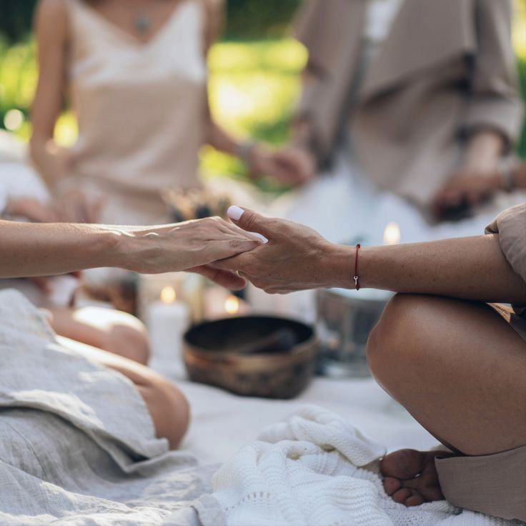 Mãos dadas num círculo de mulheres, com taça tibetana e velas